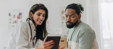 Female doctor talking to male patient looking at iPad device